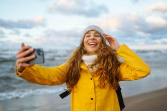 Woman travel blogger takes selfie for social networks by sea sunset. Travel, tourism, relax concept